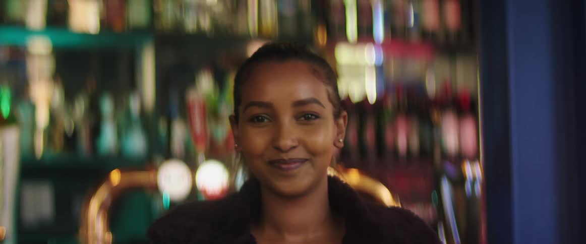 A young woman smiling for a portrait while adjusting her jacket on her shoulders