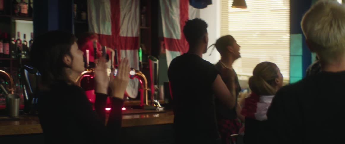 British football fans watch football on television celebrating goal in bar