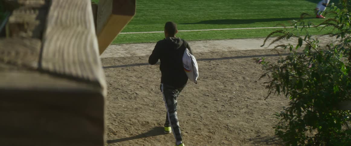 A man walking down outdoor steps towards a grassy soccer field