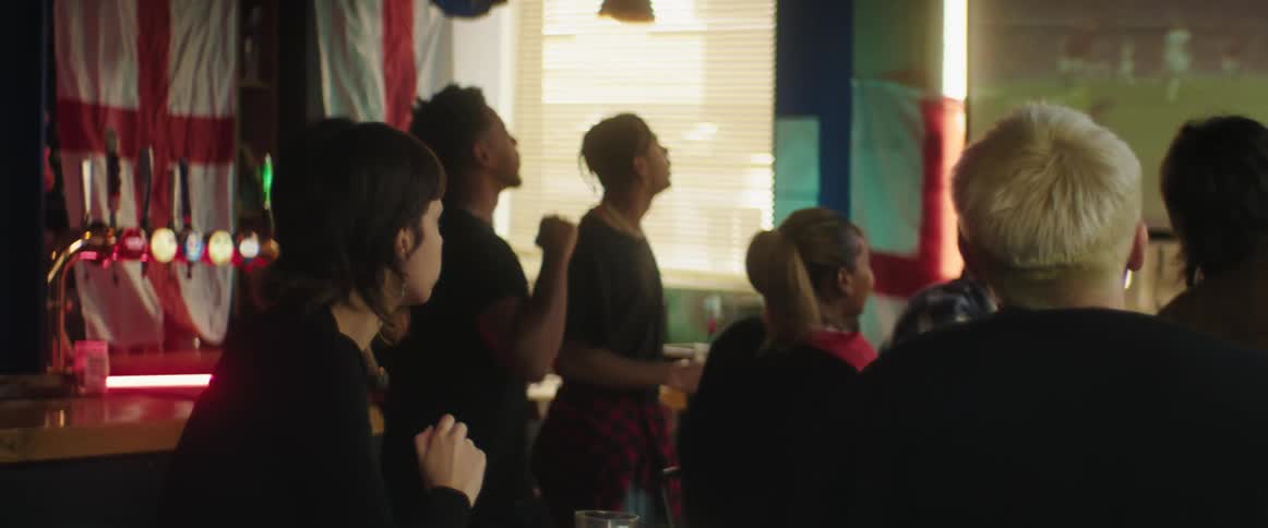 British fans watching football match on television celebrate goal in bar