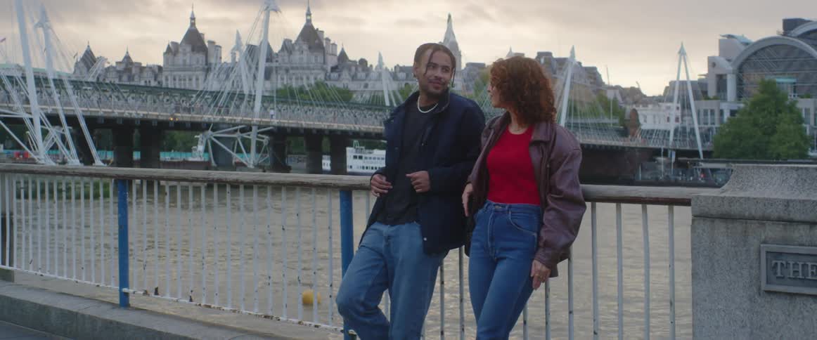 Man and woman are standing on a bridge and talking to eachother