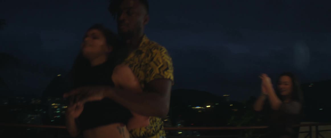 A group of people are dancing outdoors at night