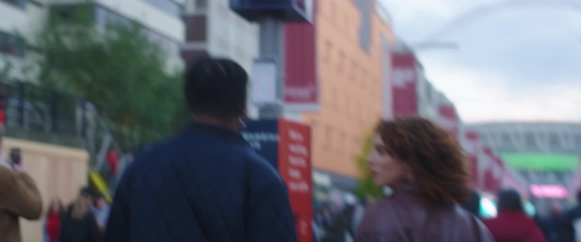 A large crowd is walking through a downtown city