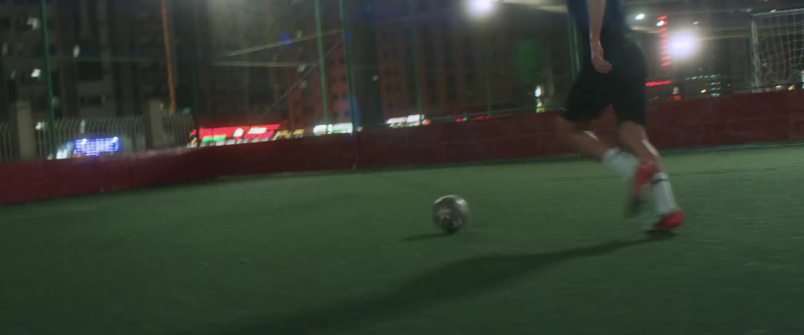 A man kicks a soccer ball down a field and kicks it in to the goal