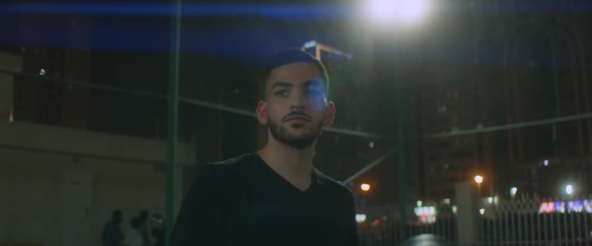 A man is holding a soccer ball while standing outdoors at night