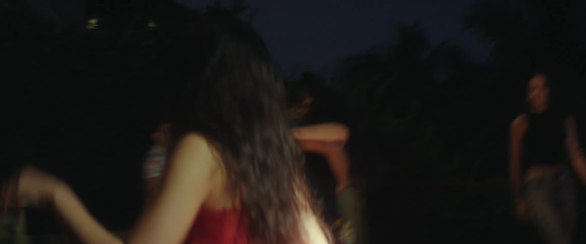 Group of friends circling a dancing couple outdoors at night