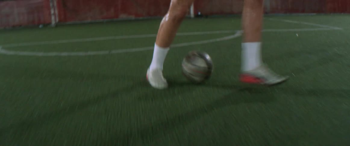 A man dribbles a soccer ball on an outdoor soccer field