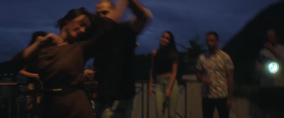 A group of people are dancing outdoors at night