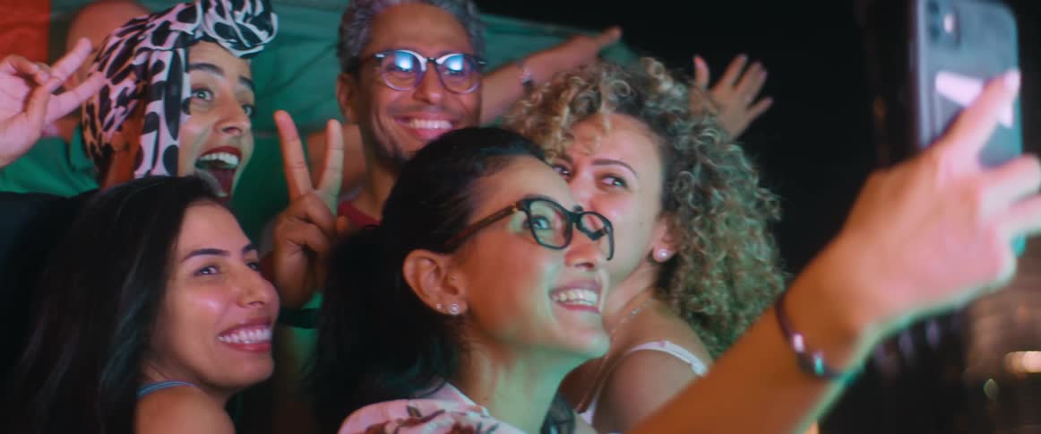 A group of friends are taking a selfie together with a smart phone