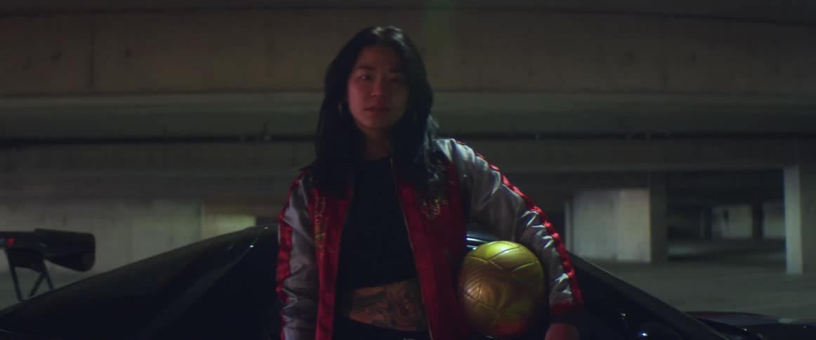 A woman is standing by her parked car while holding a soccer ball