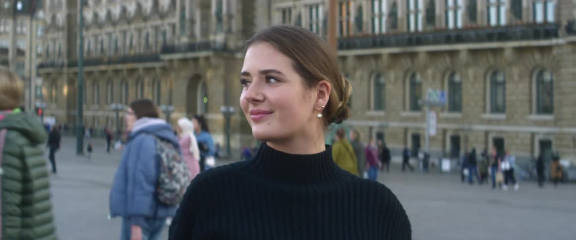 Woman poses for photos in front of a large building in a city square