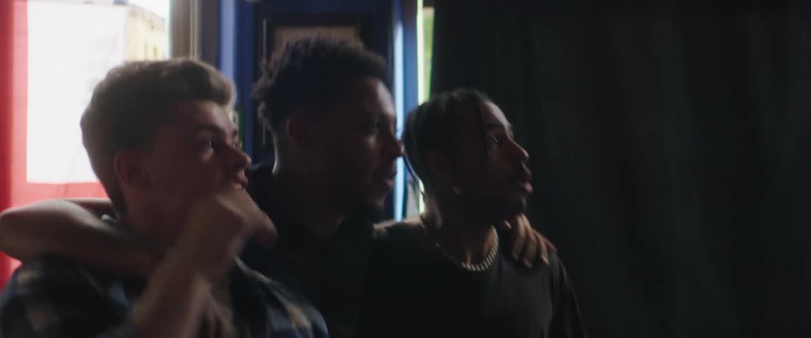 Three men cheer at something they are watching