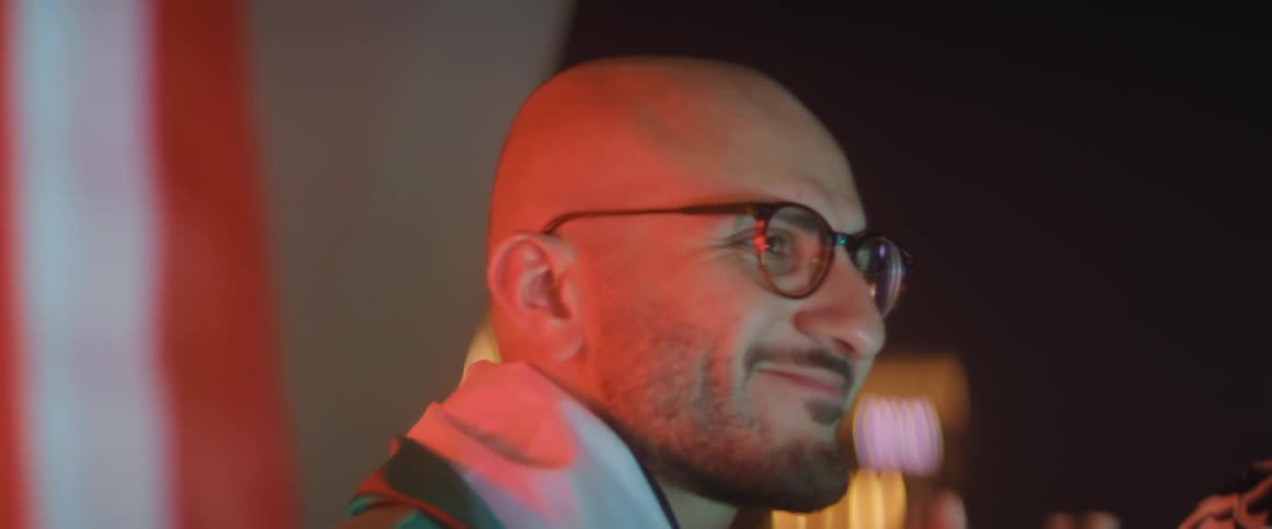 A bald man smiling and applauding while spectating