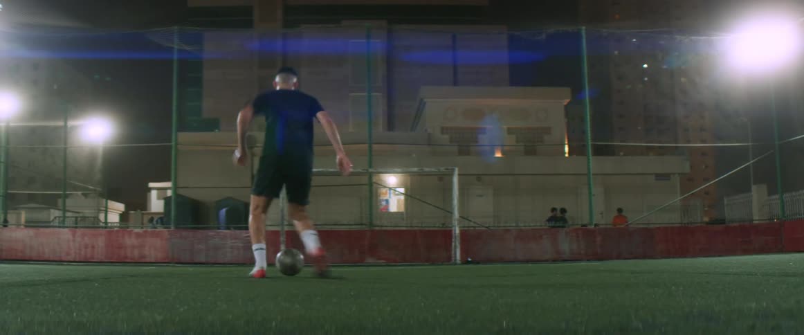 People watch as a soccer player practices kicking in a stadium