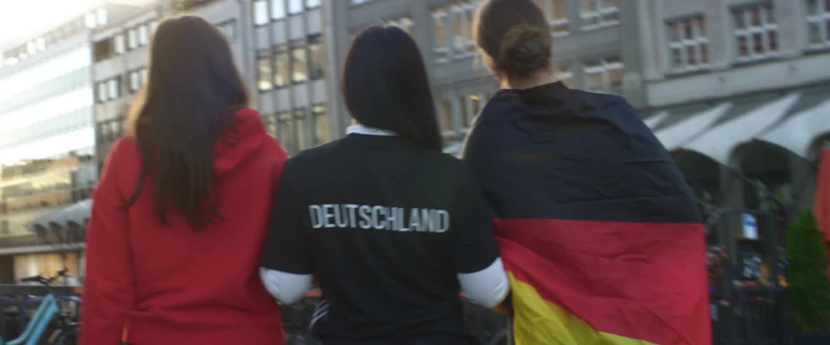 Group of friends going to a game with flags and uniforms walking on the street at evening