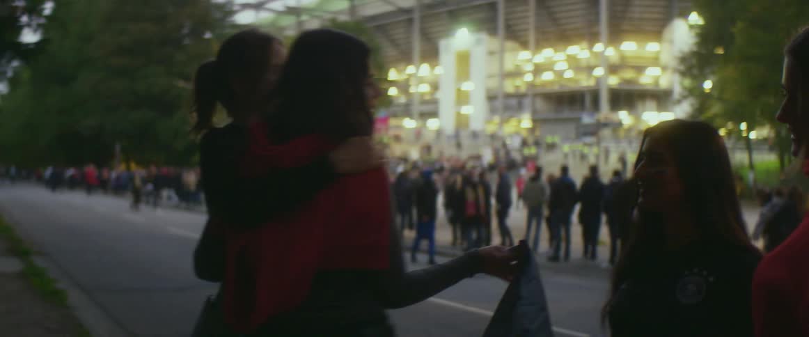 A crowd is standing outside a stadium in spring