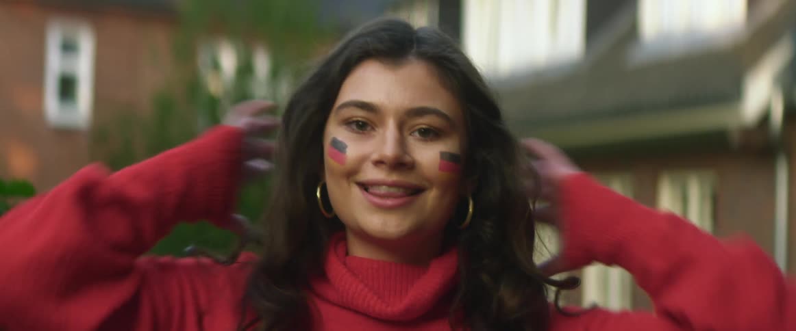 Teenage asian girl with face paint on her cheeks smiles as she fixes her long dark hair with her hands