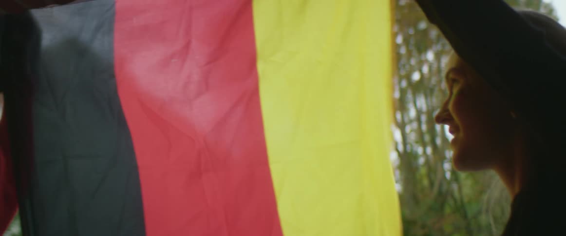 Two friends are putting up a flag outdoors in spring