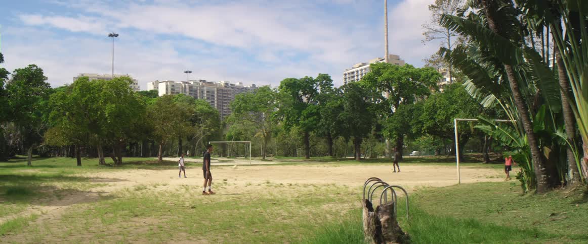 Group of friends playing soccer on a field in the park on the city