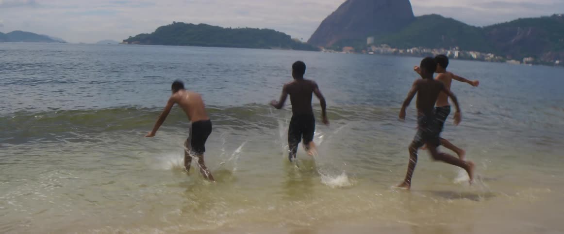 A group of youth runs to the sea next to the beach