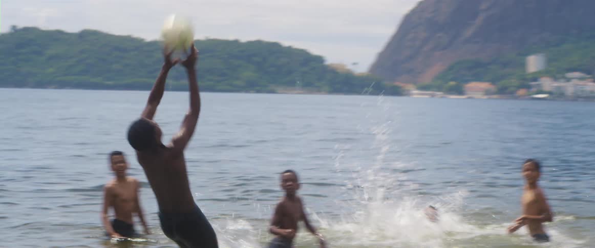 Group of boys playing volleyball on the water in the beach