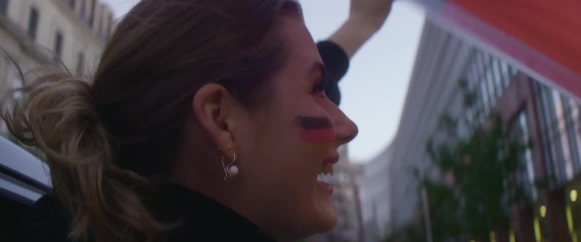 A woman holding a flag is riding in a car through a downtown city