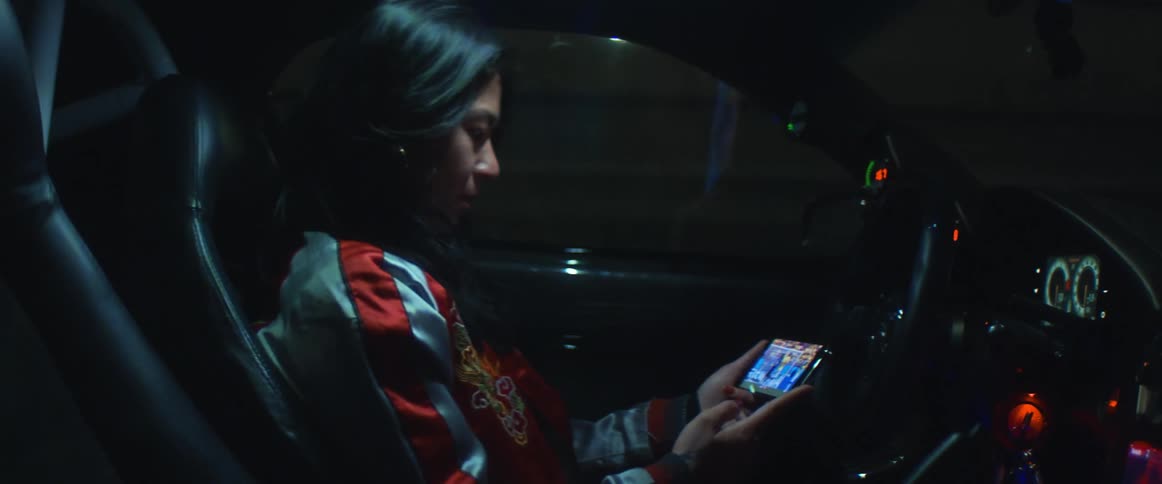 A woman is sitting in a car and watching a video on a cellphone