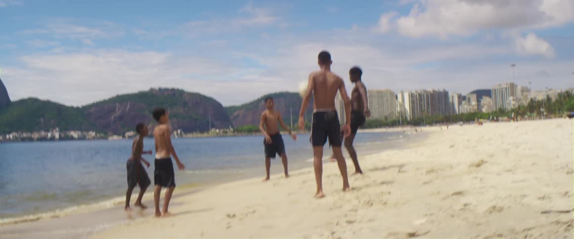 Group of friends playing with a volleyball on a beach near the ocean in brazil