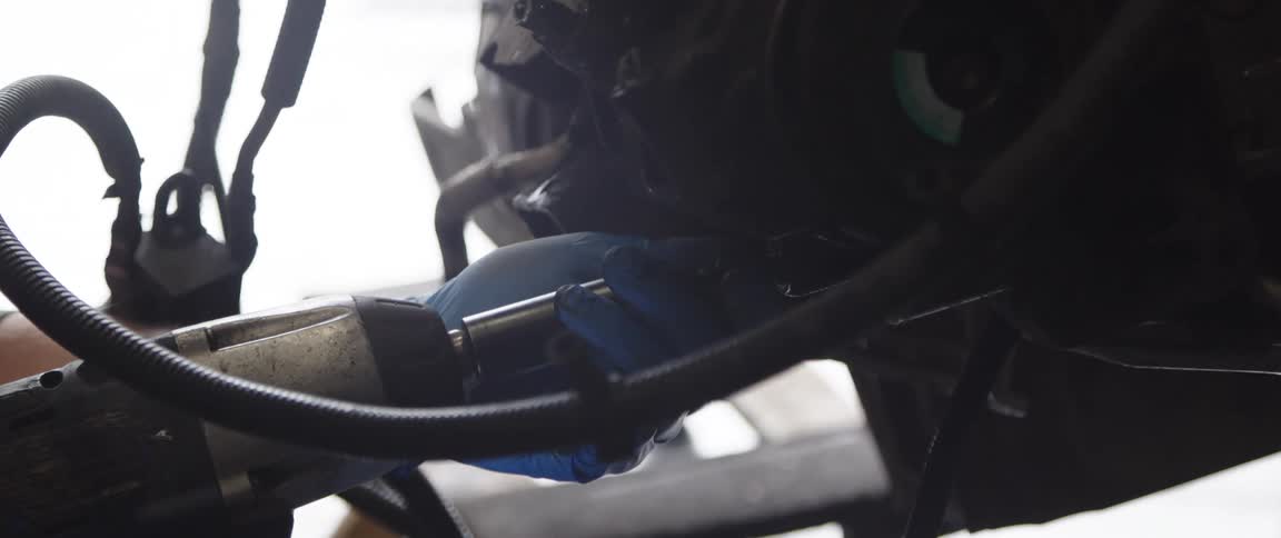 Person uses power tool on engine