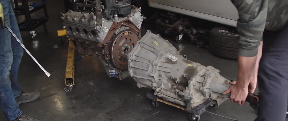 Two men are taking a part a car engine