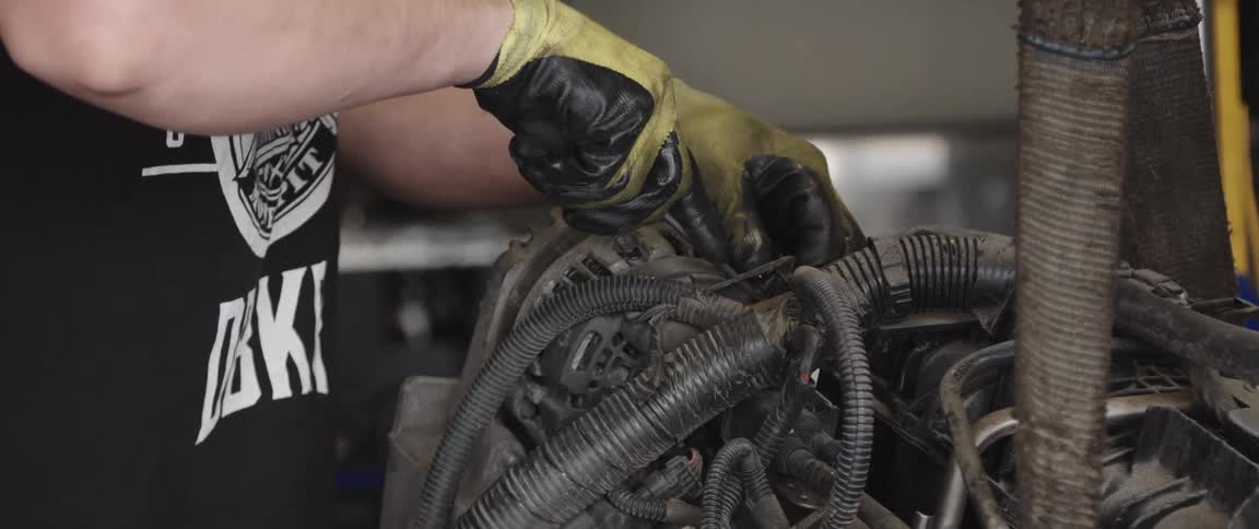 Mechanic with black shirt and gloves repairs engine at garage