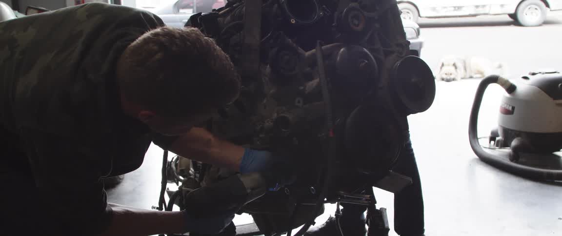 Mechanic with military shirt repairs the engine at the garage