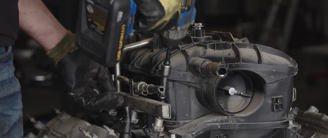 A man is using a drill on the engine