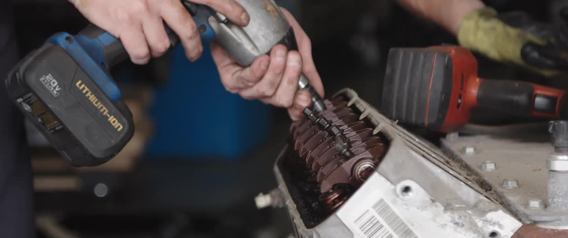 Man uses battery operated power tool on machine