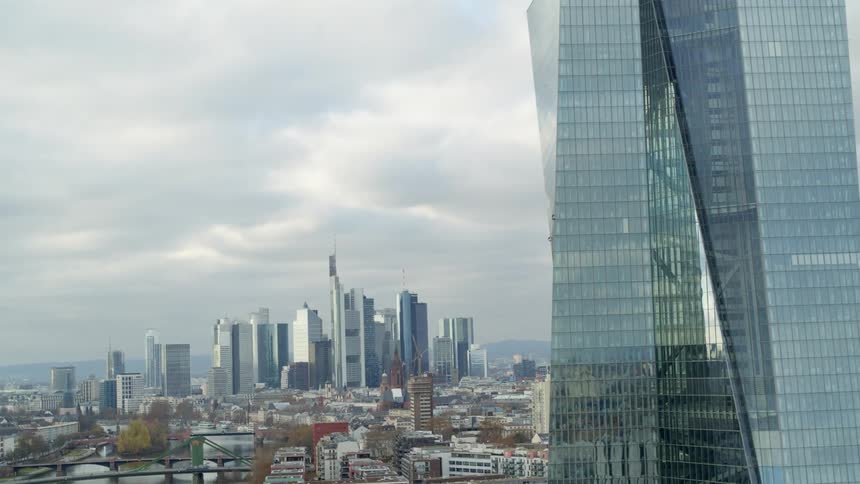 Aerial view of the glass facade of a tall skyscraper near the city skyline