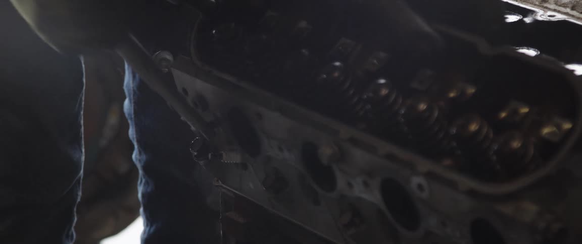 A man uses a wrench to tighten a bolt on an engine