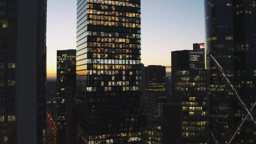 Red horizon reflects from glass on skyscrapers with lit rooms