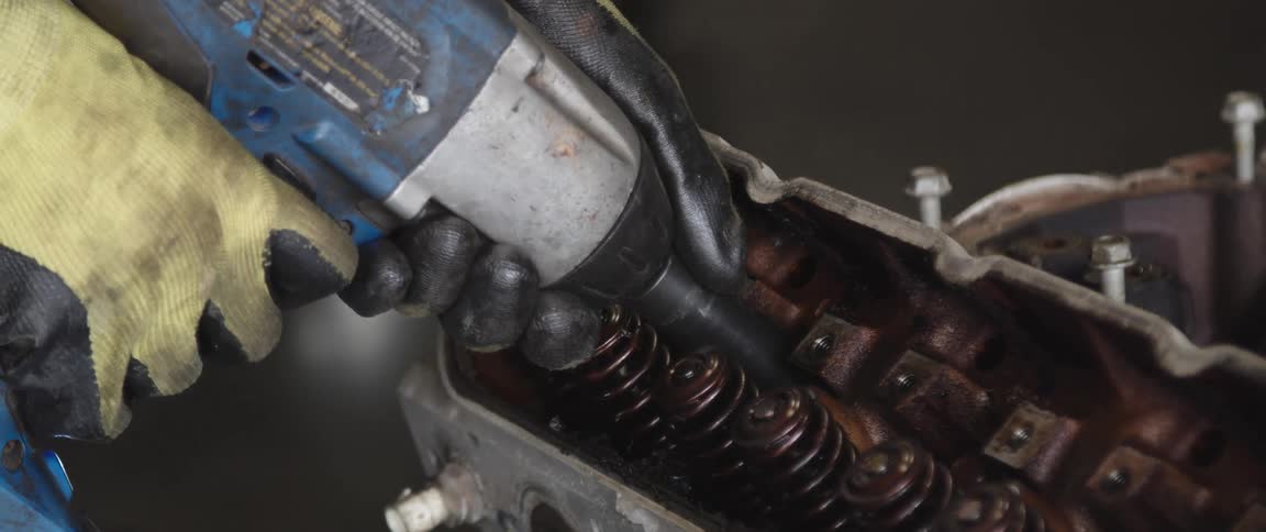 Person wears gloves while using handheld power tool on machinery