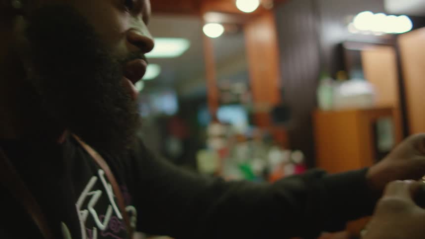 A barber chats with a client while shaving his hair