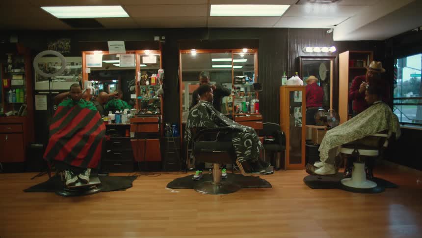 Three men are getting haircuts in a barber shop