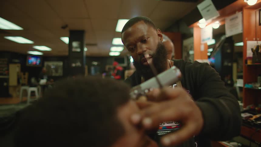 A barber trims a mans hair in a barber shop