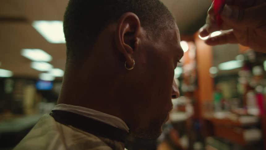 A man at a barber shop getting his hair combed
