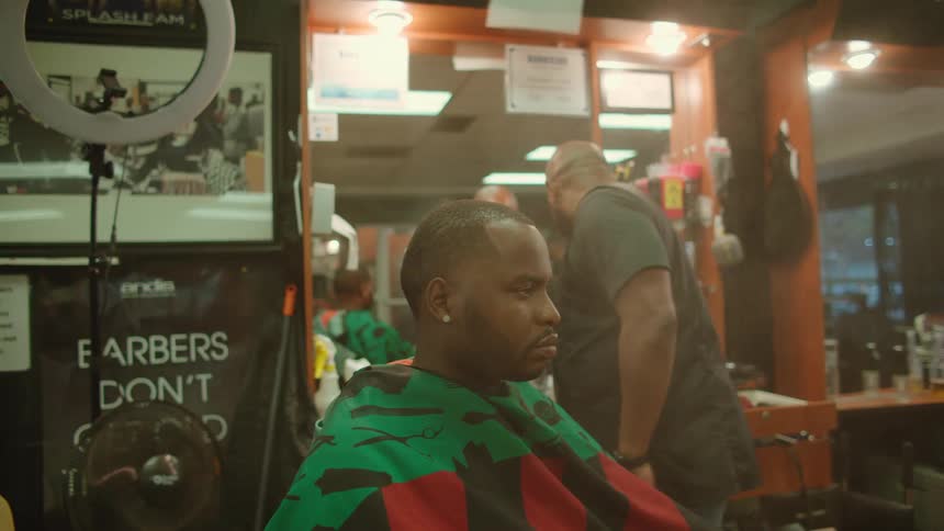 A barber spraying a customers hair with an aerosol can in a barbershop