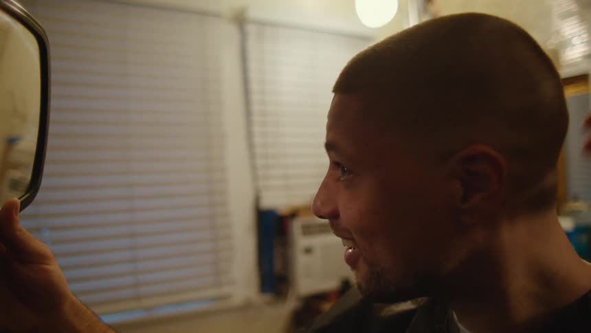 Young man admires his new haircut on a mirror inside a barber shop