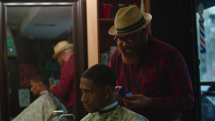 A male barber giving a man a haircut in a barbershop
