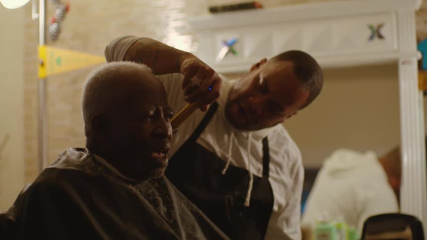 A barber giving an elderly man a haircut in a barbershop