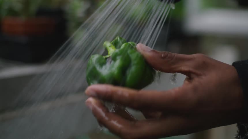A person is outdoors and rinsing a vegetable off