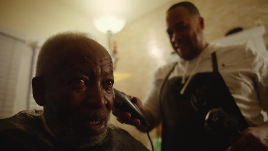 Barber talks to client while using hair clippers on his hair