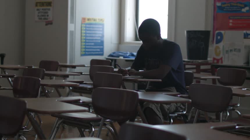 A boy sits in an empty classroom
