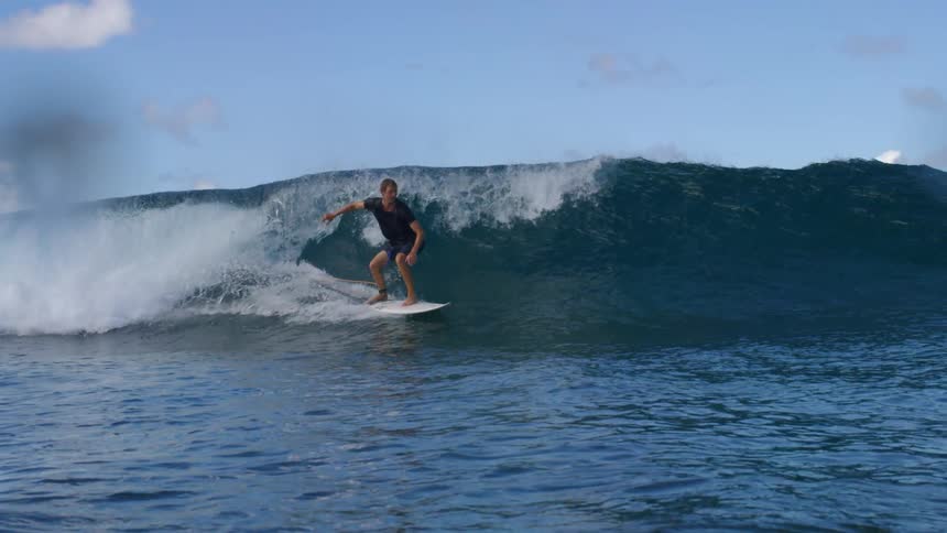 A surfer rides in front of a wave on the ocean during the day